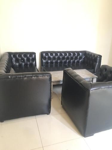 two black leather couches and a coffee table in a room at Apple Luxury Apartments in Kigali