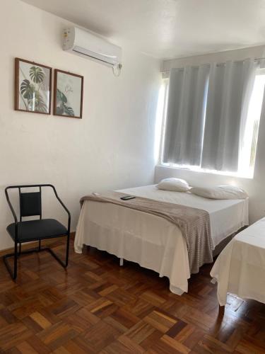 a bedroom with a bed and a chair and a window at Hotel LENA in São Luiz Gonzaga