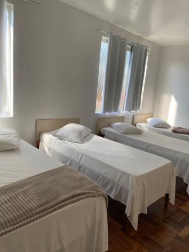 a room with three beds and two windows at Hotel LENA in São Luiz Gonzaga