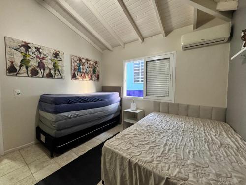 une chambre avec un lit, un canapé et une fenêtre dans l'établissement CASA PINHEIROS - Casa na Praia de Palmas com 4 Dormitórios e Piscina, à Governador Celso Ramos