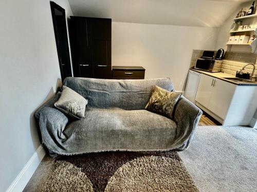 a couch in a living room with a kitchen at Guest Room by Amanda & David in Devizes Wiltshire in Bishops Cannings