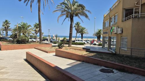 ein Gebäude mit Palmen neben einem Parkplatz in der Unterkunft Studio au pied de l'eau in Canet-en-Roussillon