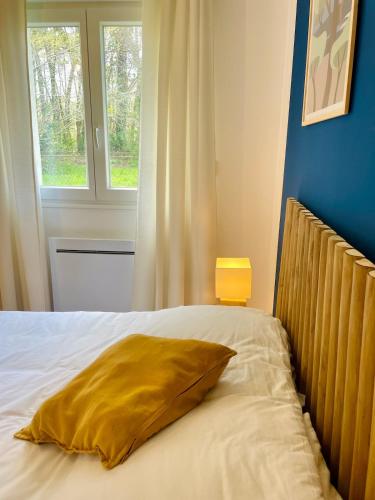 a bed with a yellow pillow and a window at Maison climatisée 3 chambres avec jardin in Pontenx-les-Forges