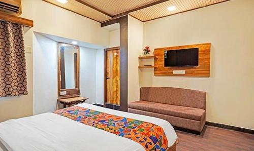 a bedroom with a bed and a couch and a tv at Hotel Bridge in Ahmedabad