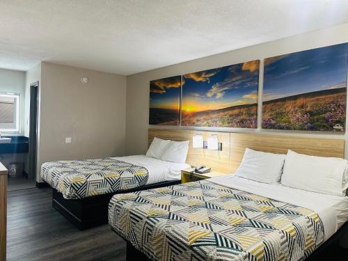 a hotel room with two beds and a painting on the wall at Days Inn by Wyndham Kansas City Northeast in Kansas City