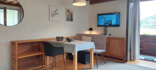 a dining room with a table and chairs and a television at Apartment am Wolfgangsee in Strobl