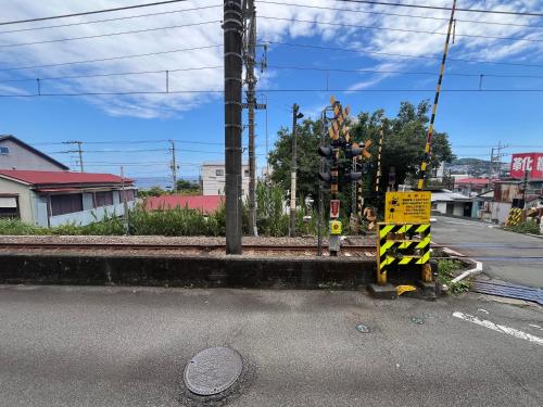 a pole with a caution sign on a street at 窓際から海と鉄道が見える宿 サウナ プロジェクター カラオケ完備 トリックマーメイド in Ito