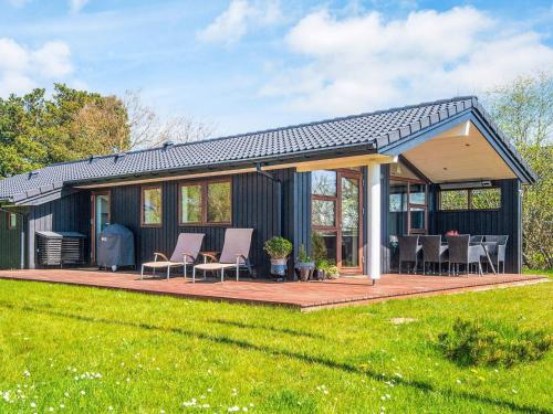a small black house with a deck and chairs at 4 star holiday home in Rømø in Lakolk