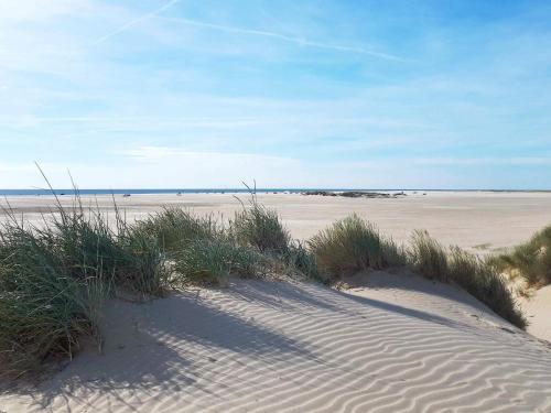a sandy beach with grass and footprints in the sand at 4 star holiday home in Rømø in Lakolk