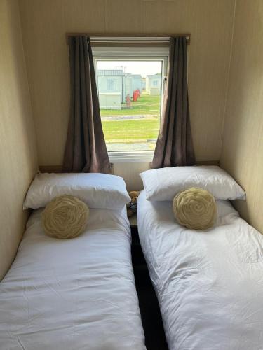 two beds in a small room with a window at Caravan at the seaside in Great Yarmouth