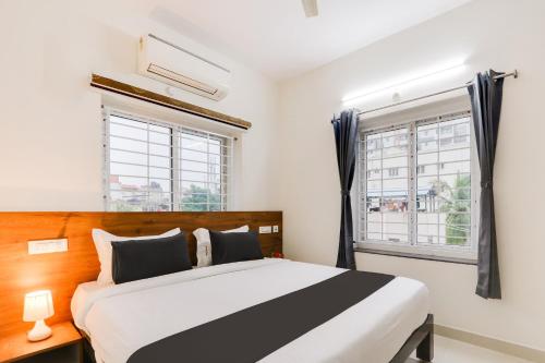a bedroom with a bed and two windows at Super Townhouse Sri Nirvana Grand in Hyderabad
