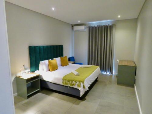 a bedroom with a large bed with yellow pillows at The Executive - Exclusive Self-Catering Apartments - Ezulwini in Ezulwini
