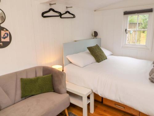 a bedroom with a bed and a couch and a chair at King's Cwtch Shepherd's Hut in Cardiff