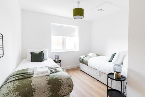 two beds in a bedroom with white walls and wood floors at Sleek & Cozy 2BR Apartment for Your Stay # 3 in Rothley
