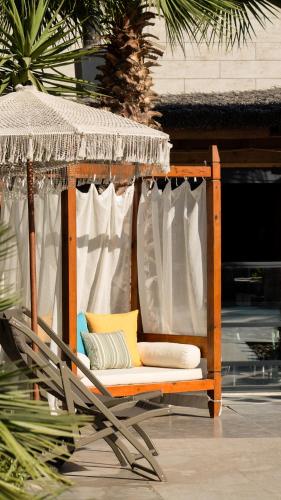 a swinging chair with pillows and a straw umbrella at Rammos Managed By Dedeman in Bodrum City