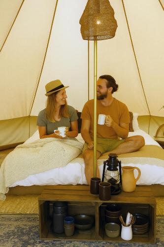a man and woman sitting on a bed in a tent at Langeland Camping in Rudkøbing