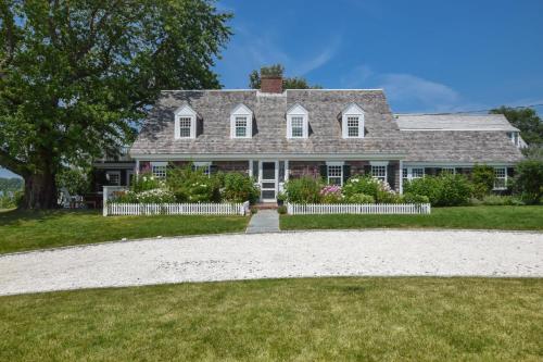 a gray house with a white fence and a yard at Large waterfront home with direct beach access in Dennis