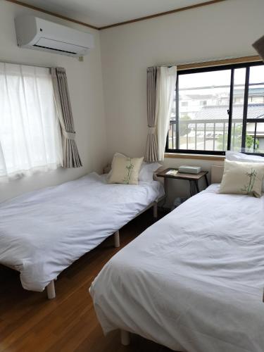 two beds in a room with a window at 世界文化遗产三保松原 徒步3分钟 和服体验 160平独栋日式民居 民宿 松原 in Shizuoka