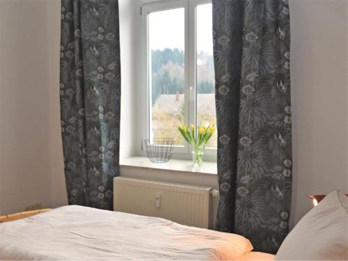 a bedroom with a window with a vase of flowers at Retreat in the Ore Mountains in Wünschendorf