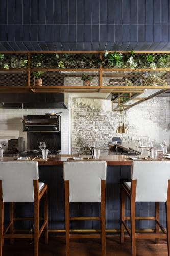 a kitchen with a bar with white chairs at Hotel Richemont in Charleston