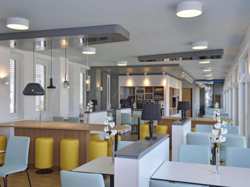 a restaurant with yellow and white chairs and tables at B&B Hotel Halle (Saale) in Halle an der Saale