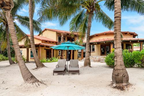 a house with two chairs and an umbrella on the beach at Seascape Villas in San Pedro
