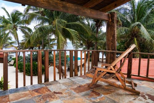 a wooden chair sitting on a balcony overlooking the ocean at Seascape Villas in San Pedro