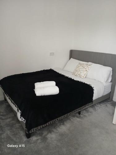 a bed with two white towels on top of it at Luton Homes in Luton