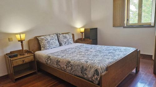 Un dormitorio con una cama con dos mesitas de noche y dos lámparas. en Gerês ZEN by Gerês Casas, en Gerez