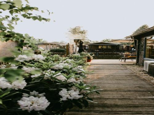 a wooden walkway with white flowers in a yard at Geel Chalet in Netevallei in Geel