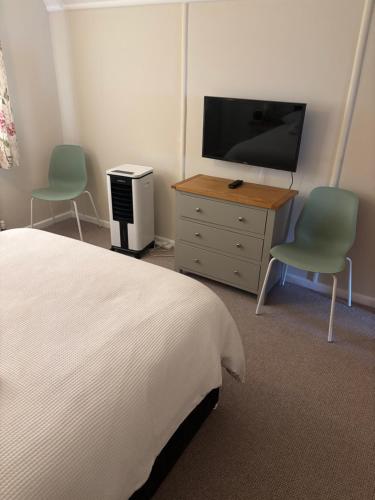a bedroom with a bed and a tv and two chairs at Ideal Family Holiday home Exmouth in Exmouth