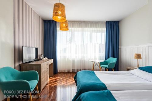 a hotel room with a bed and a television at Ach Mazury in Mikołajki