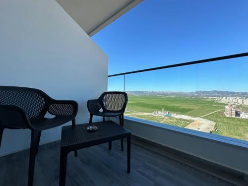 two chairs and a table in a room with a large window at Grand Sapphire One Bedroom Luxury Residences By MyGuest Cyprus in Iskele