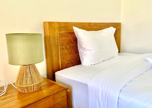 a bedroom with a bed and a lamp on a night stand at Bali Stuti Jimbaran Inn in Jimbaran