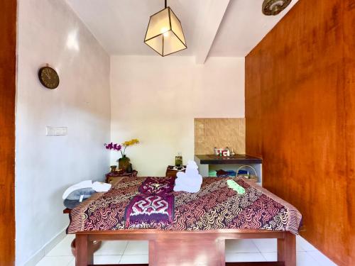 a bedroom with a bed with a purple blanket at Bali Stuti Jimbaran Inn in Jimbaran