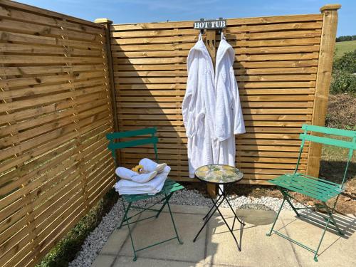 a pair of chairs and robes hanging on a fence at Charming shepherds hut with hottub in Umberleigh Bridge