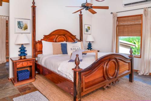 a bedroom with a large wooden bed and a fan at Seascape Villas in San Pedro