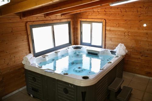 a jacuzzi tub in a room with two windows at בקתות ההוד in Kallanit