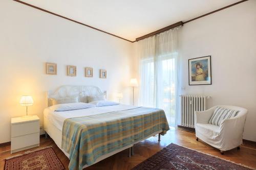 a white bedroom with a bed and a chair at Hotel Ancora in Verbania