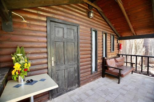 a wooden cabin with a door and a bench on a patio at בקתות ההוד in Kallanit