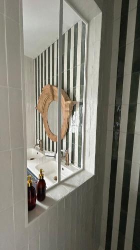 a mirror on a shelf in a bathroom with a sink at La Maison Mulatô, demeure privée d'hôtes, piscine & spa Libourne, Saint-Emilion in Libourne