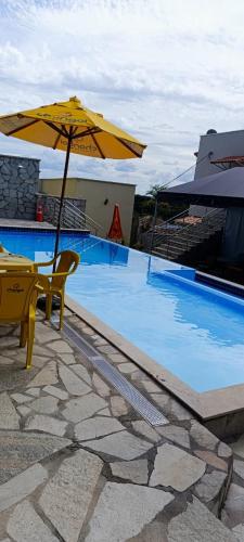 a pool with a yellow umbrella and a table and chair at Hotel e Pousada Vila Boa in Goiás