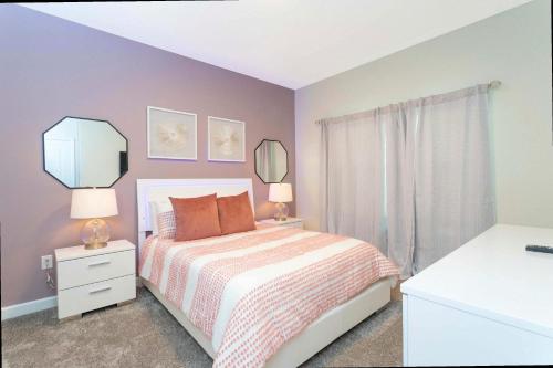 a bedroom with a bed and two lamps and a mirror at Gorgeous 4 Bd w/ Pool at Champions Gate Resort 1020 in Orlando