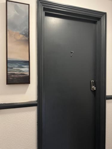 a black door with a picture on the wall at Magic Stay Rooms in London