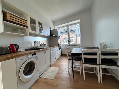 a kitchen with a washing machine and a table with chairs at Appartement romantique de luxe à Liège Chambre, salon SDB privée 2e étage in Liège