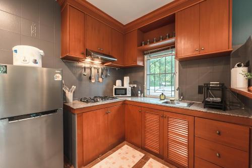 a kitchen with wooden cabinets and a stainless steel refrigerator at Areca Holiday Home 8, Bangtao Beach in Ban Thalat Choeng Thale