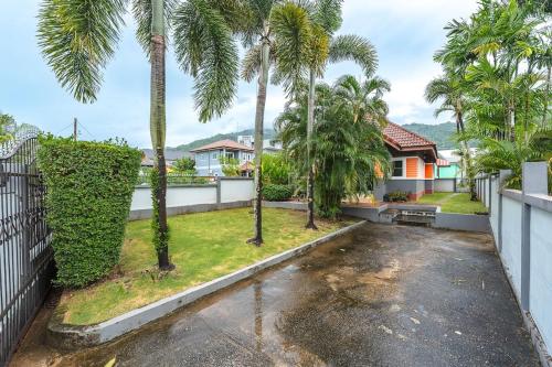 a yard with palm trees and a house at Areca Holiday Home 8, Bangtao Beach in Ban Thalat Choeng Thale