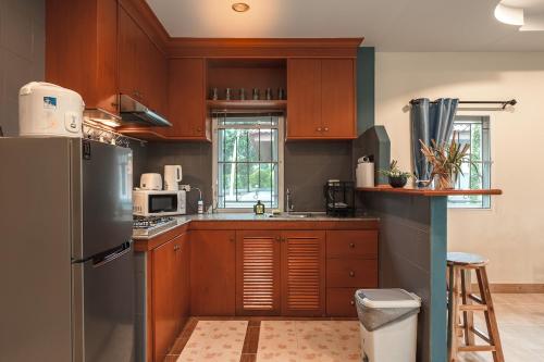 a kitchen with wooden cabinets and a stainless steel refrigerator at Areca Holiday Home 8, Bangtao Beach in Ban Thalat Choeng Thale
