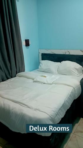 a bed with white sheets and pillows in a room at Edilom Hotel and Suites in Sapele