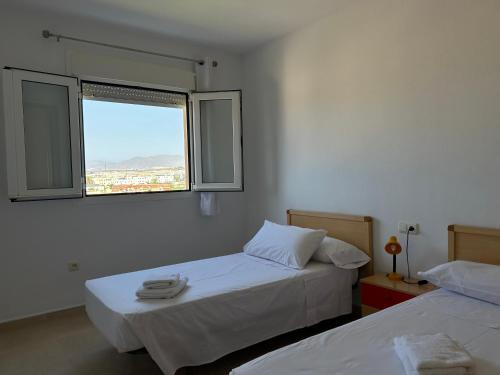 two beds in a room with a window at San Miguel Apartamentos in El Ejido